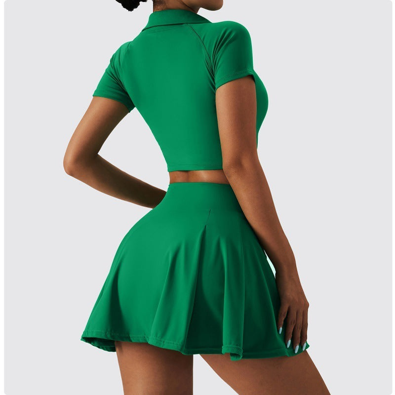 Back view of a woman wearing a green tennis set with a crop polo top and high-waisted flared skirt.