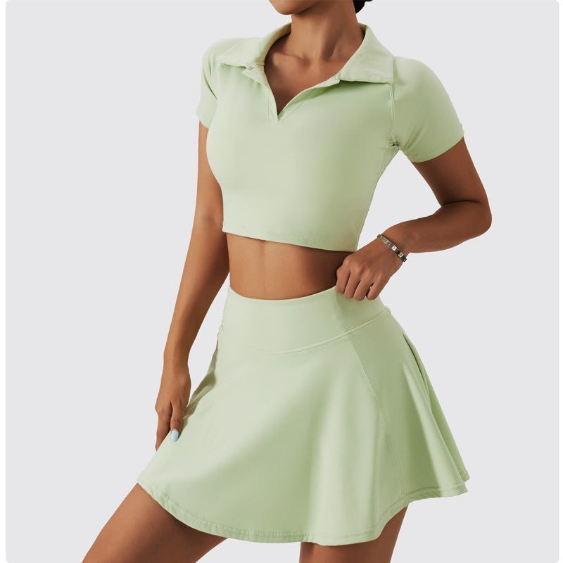 Side pose of a woman in light mint green tennis set with collared crop top and flowy skirt.