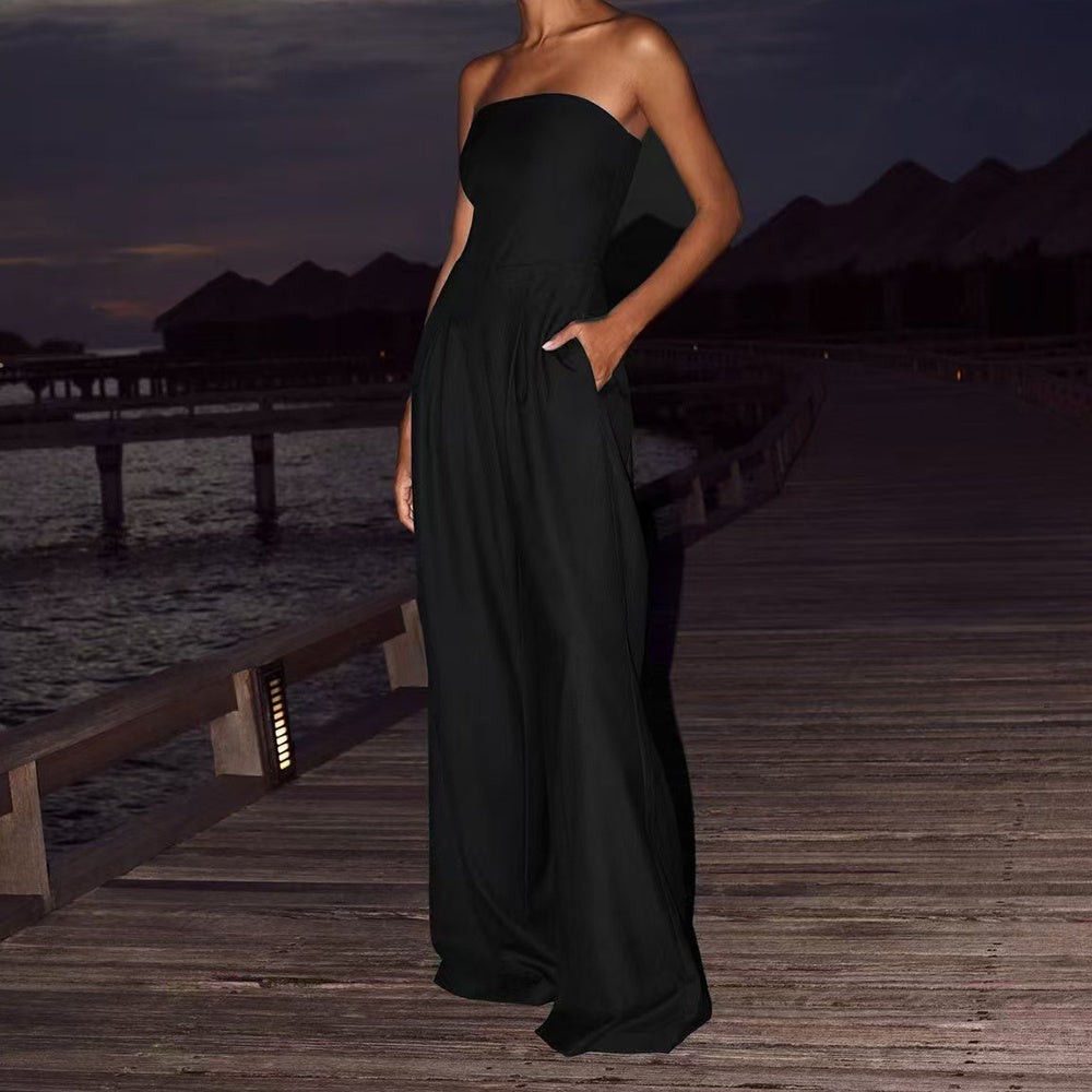 Woman wearing a strapless black wide-leg jumpsuit on a boardwalk at dusk